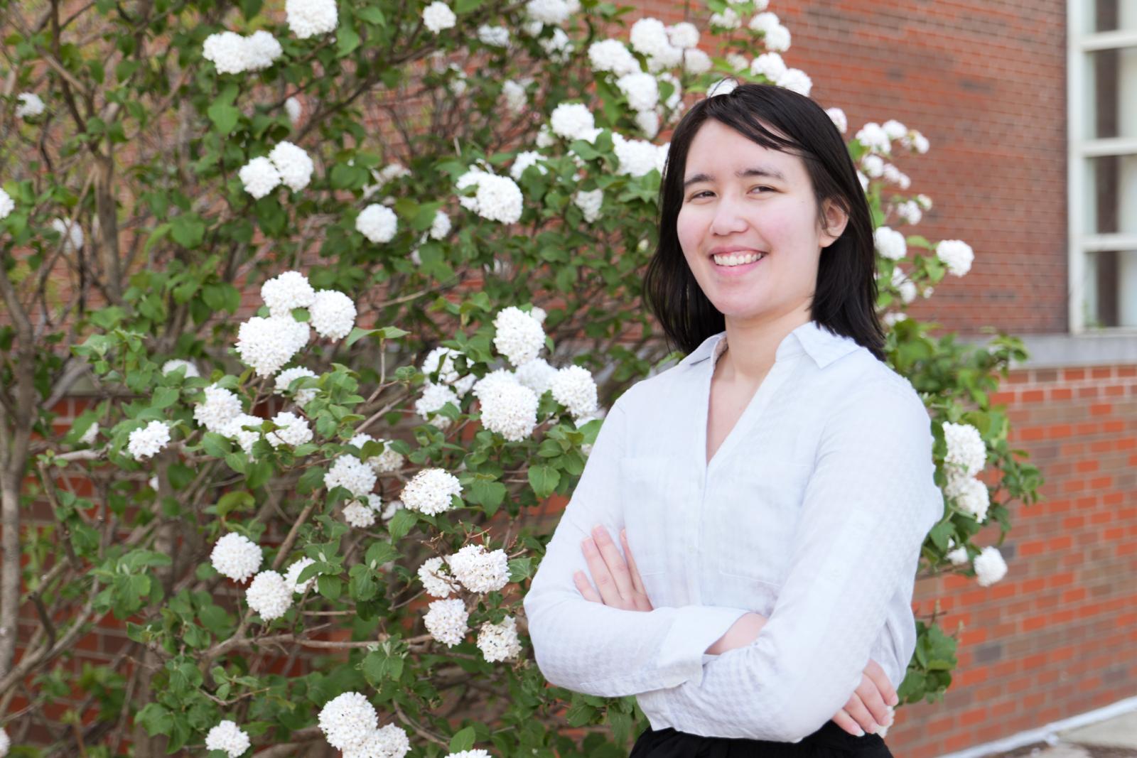Eliza Davis smiling in front of flower bush