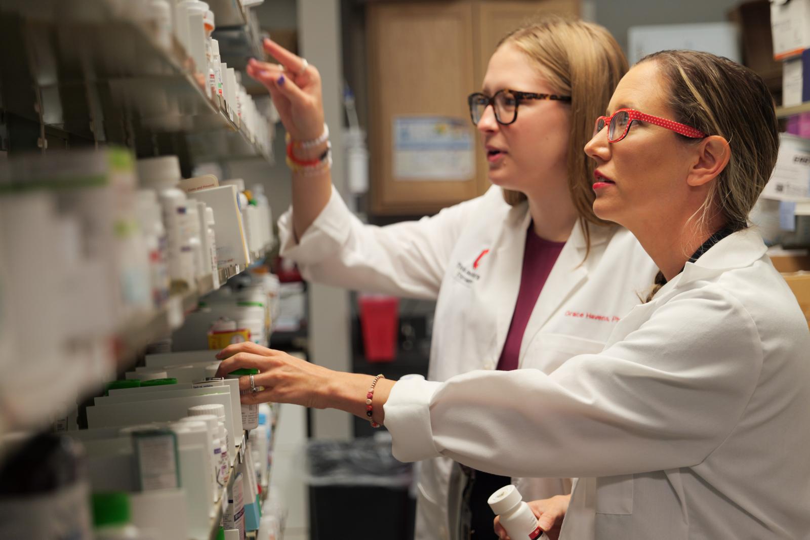 Pharmacists looking at medications on pharmacy shelves