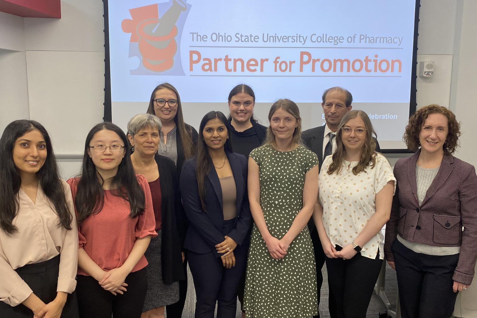 a group of people standing in front of a screen with the partner for promotion logo