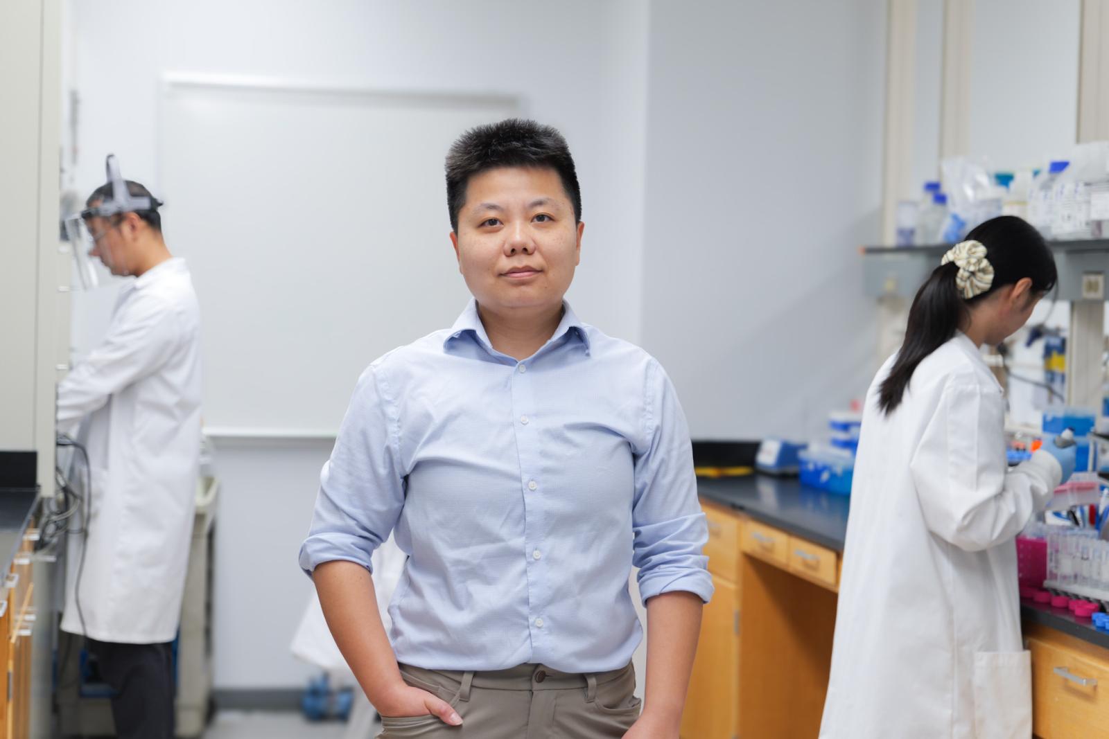 Mengying Hu standing in a lab space with student researchers
