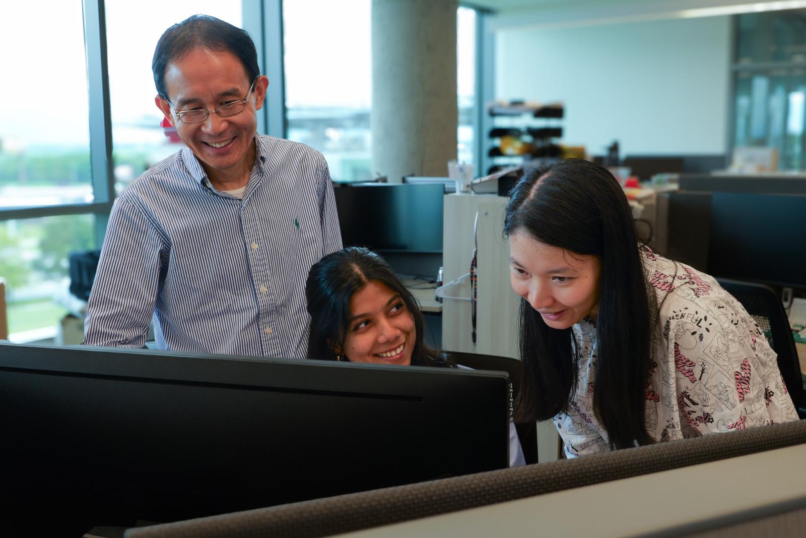 Researchers in the Cheng Lab gathered around a computer monitor